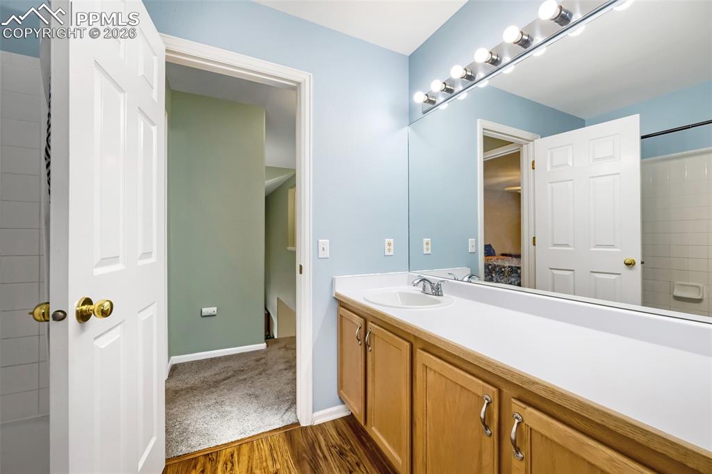 Image 28 of 32: Bathroom vanity featuring wood-finish flooring, a full-width mirror with va