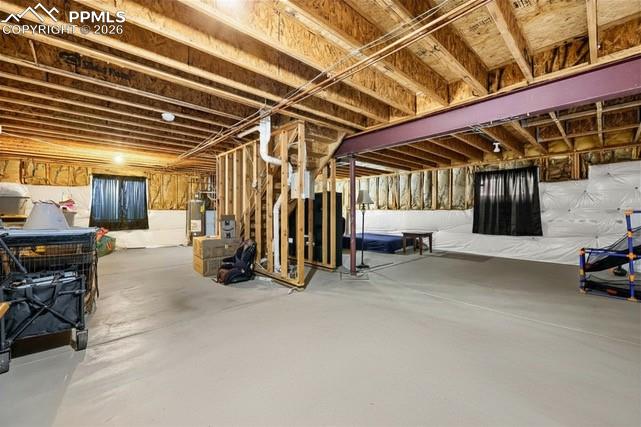 Image 29 of 32: Spacious unfinished basement with exposed wood joists and a painted concret