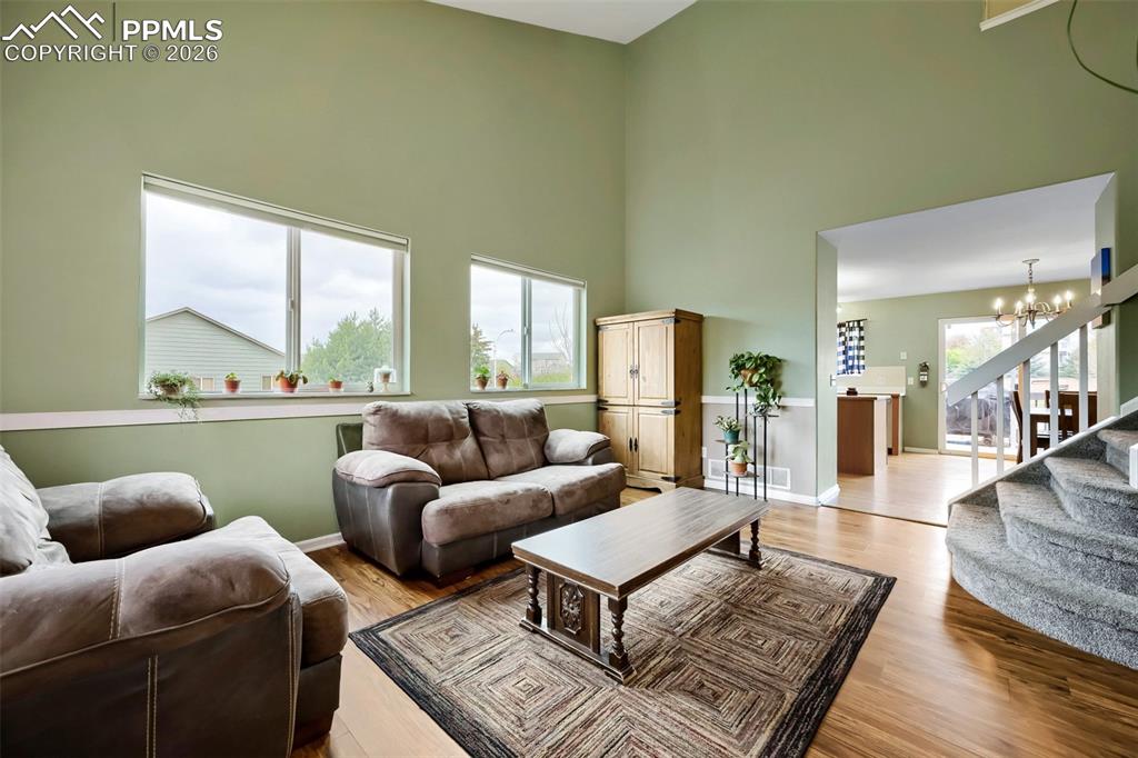 Image 5 of 32: Living area featuring high ceilings, wood-finish flooring, and multiple win