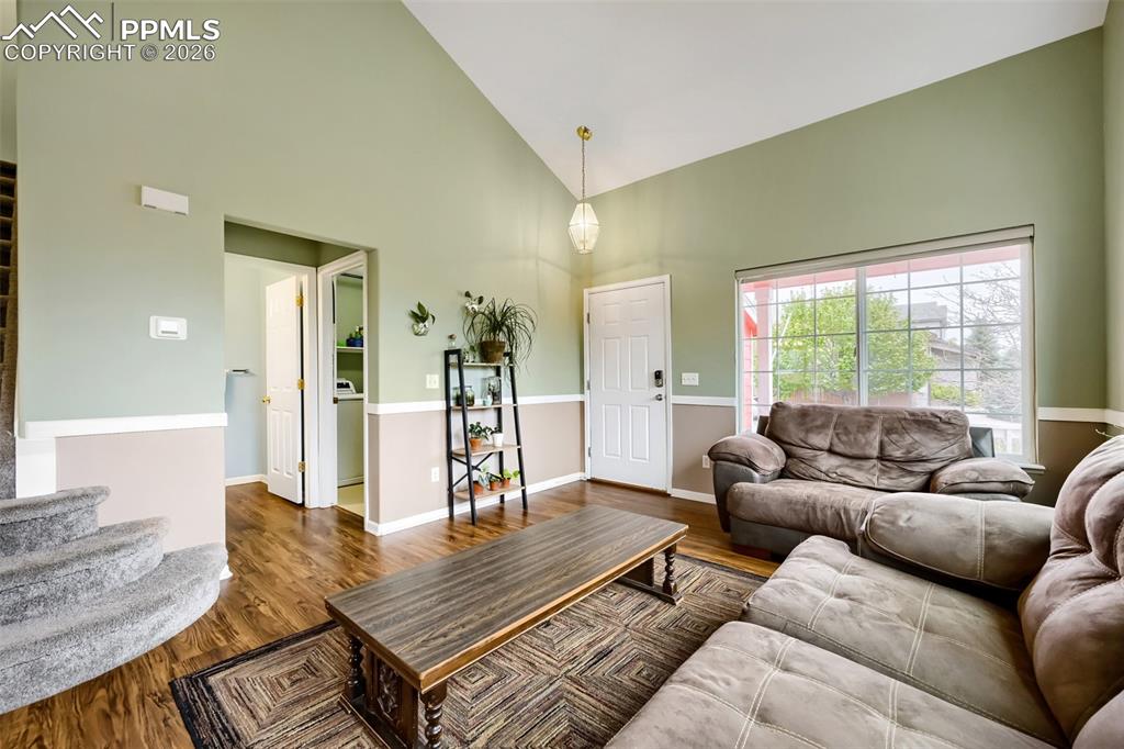 Image 6 of 32: Spacious living area featuring vaulted ceilings, wood-finish flooring, and 