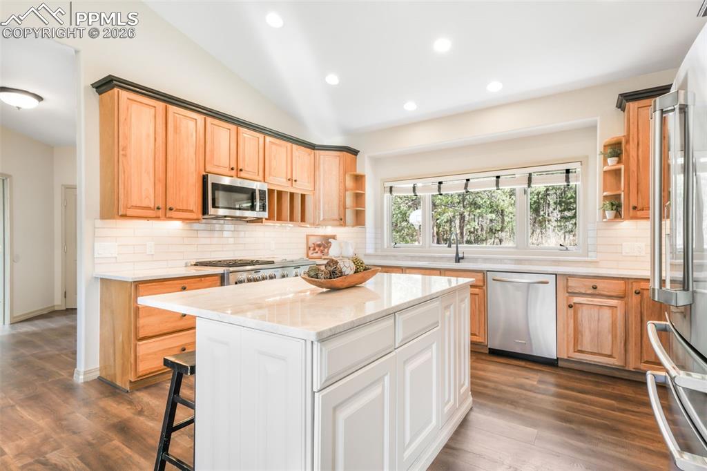 Image 25 of 50: Open-concept living space featuring vaulted ceilings, wood-finish flooring,