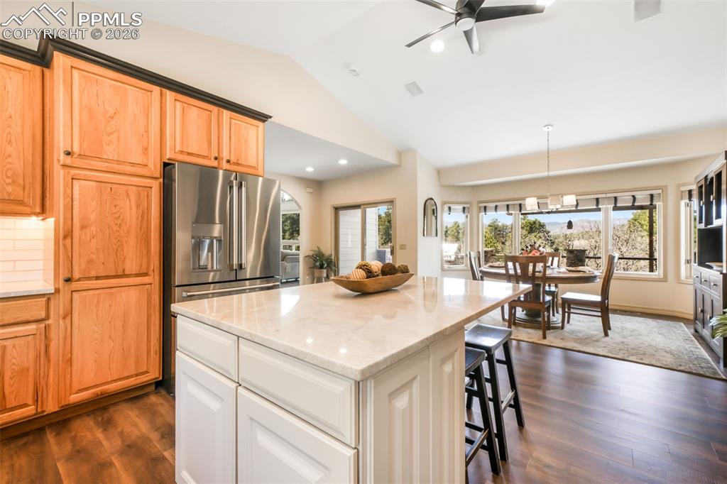 Image 28 of 50: Open-concept kitchen and dining area featuring a vaulted ceiling, wood-fini