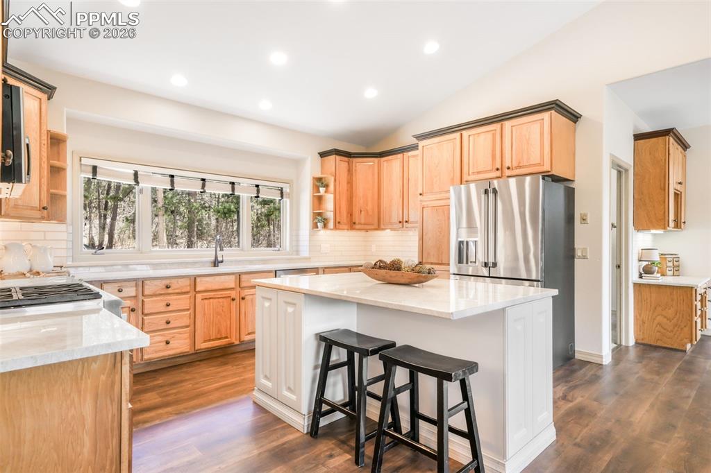 Image 29 of 50: Kitchen featuring a central island with a light-toned countertop, wood-fini