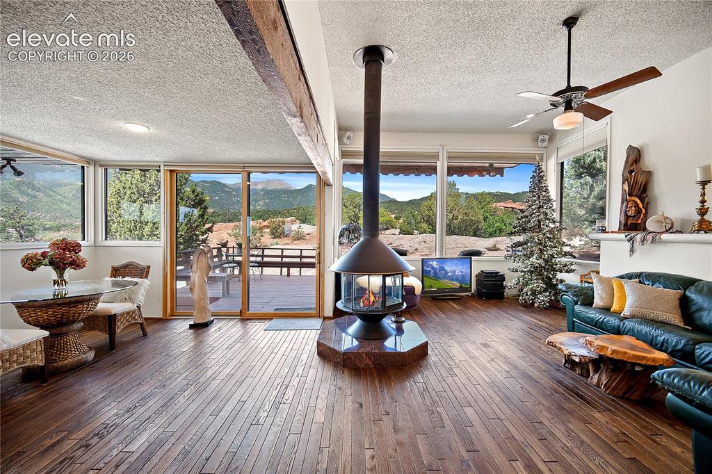 Image 13 of 47: Great room with oak flooring, wood burning stove and walk out to views of C