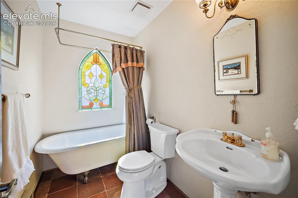 Image 9 of 47: Main level guest bedroom with clawfoot tub.
