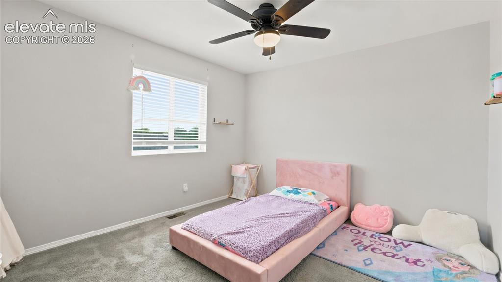 Image 22 of 50: Upper Level Bedroom #2 with neutral carpet and a lighted ceiling fan.