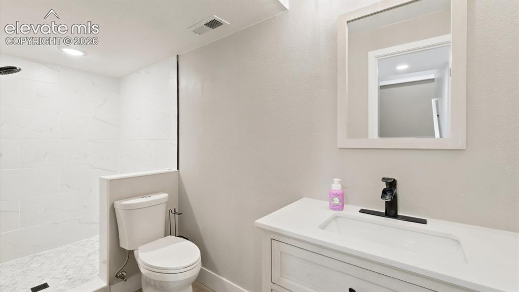 Image 37 of 50: Basement Shower Bathroom with vanity, framed mirror, and walk in tiled show