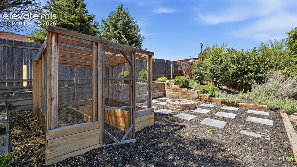 Image 43 of 50: Fabulous fenced backyard with mature trees and shrubs, a greenhouse, and fi