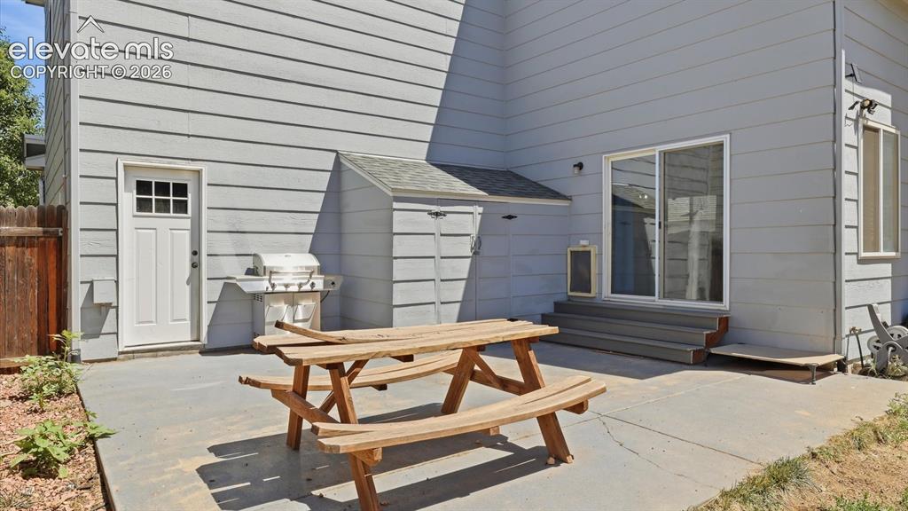 Image 45 of 50: Backyard patio for outdoor dining with a storage shed for tools and toys.