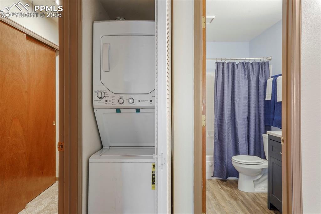 Image 17 of 50: Washroom featuring light wood-type flooring and stacked washing maching and