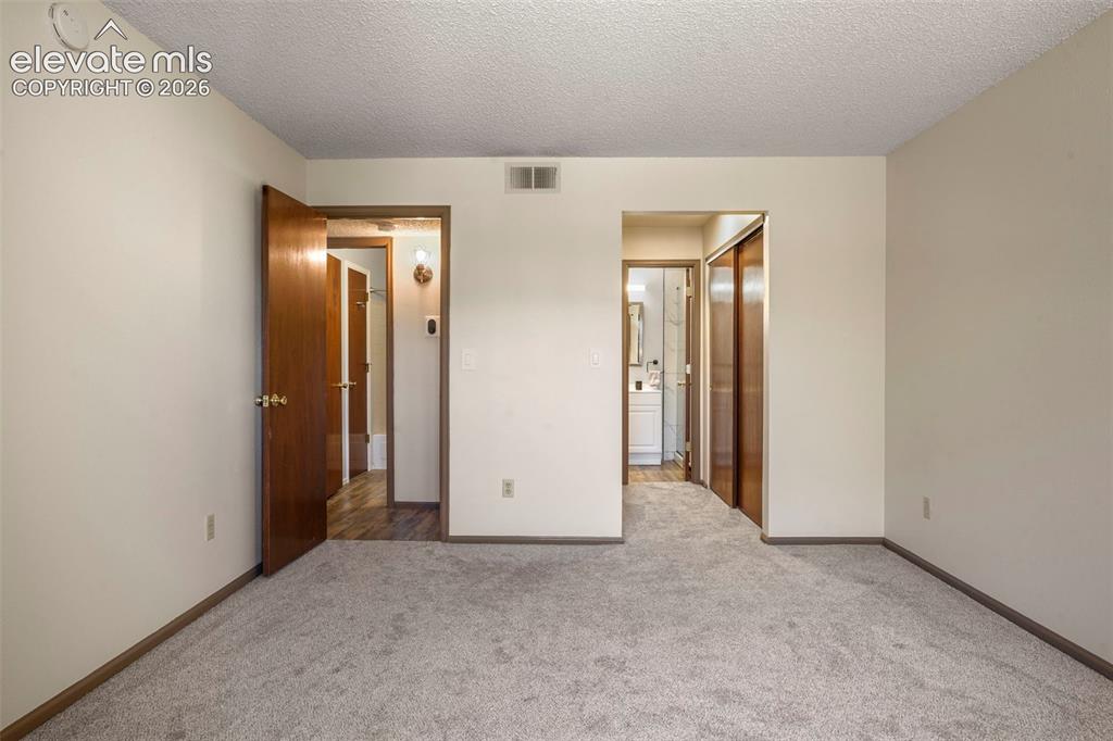 Image 18 of 50: Unfurnished bedroom featuring a closet, a textured ceiling, and light color