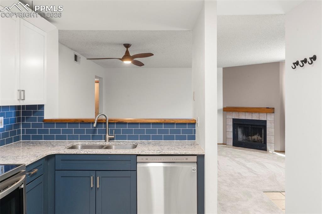 Image 35 of 50: Kitchen featuring a fireplace, stainless steel appliances, light colored ca