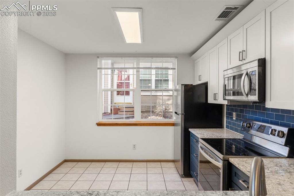 Image 36 of 50: Two tone kitchen featuring stainless steel appliances, light stone counters