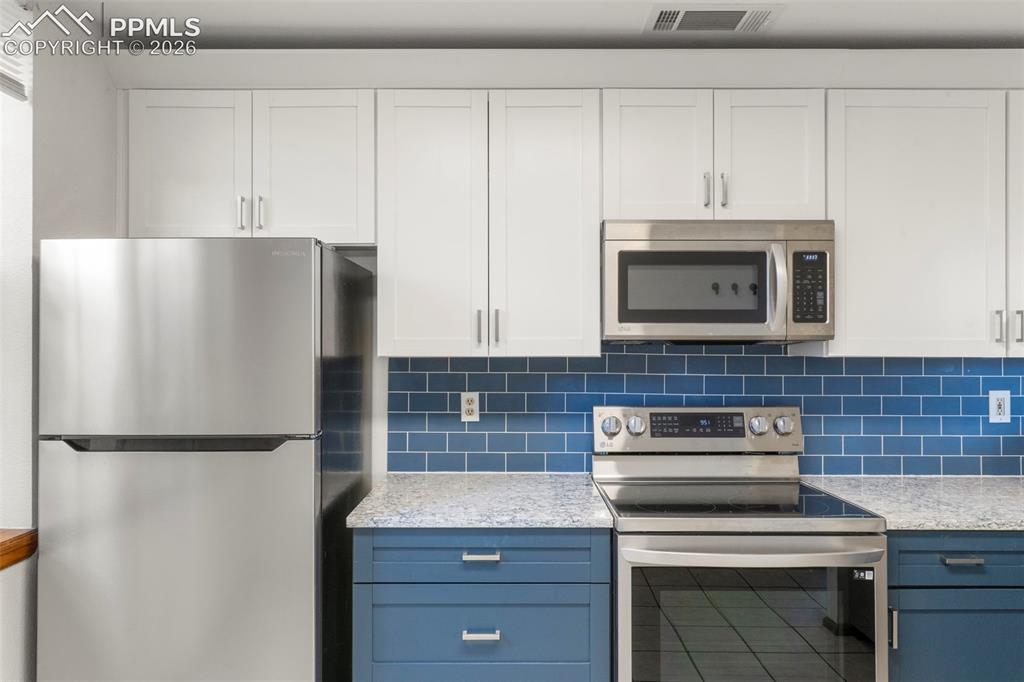 Image 37 of 50: Kitchen featuring stainless steel appliances, light stone countertops, deco