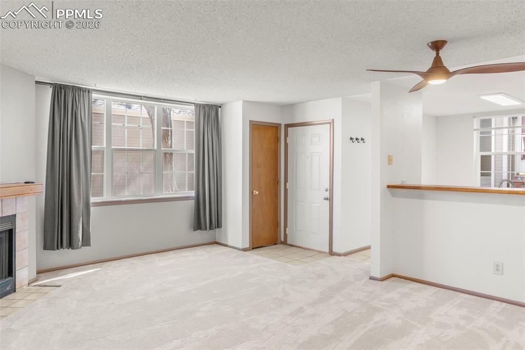 Image 40 of 50: Unfurnished living room with a tile fireplace, light colored carpet, a text