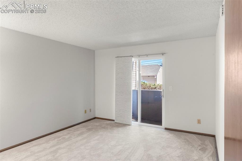 Image 41 of 50: Empty room with a textured ceiling and light carpet