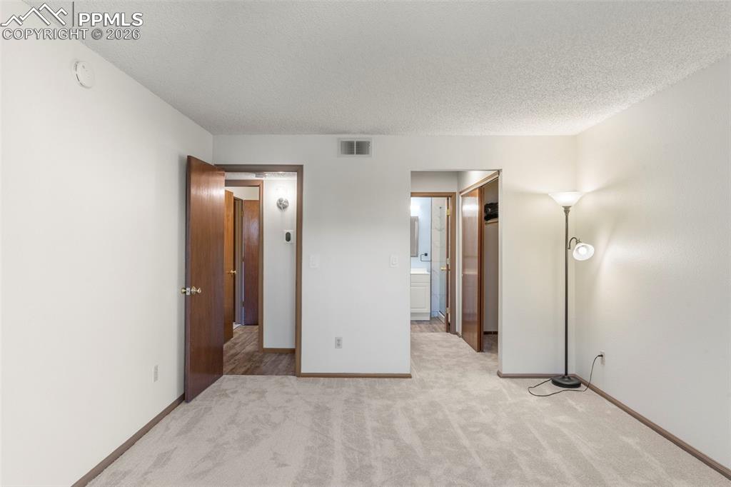 Image 42 of 50: Unfurnished bedroom with light colored carpet, a textured ceiling, and conn