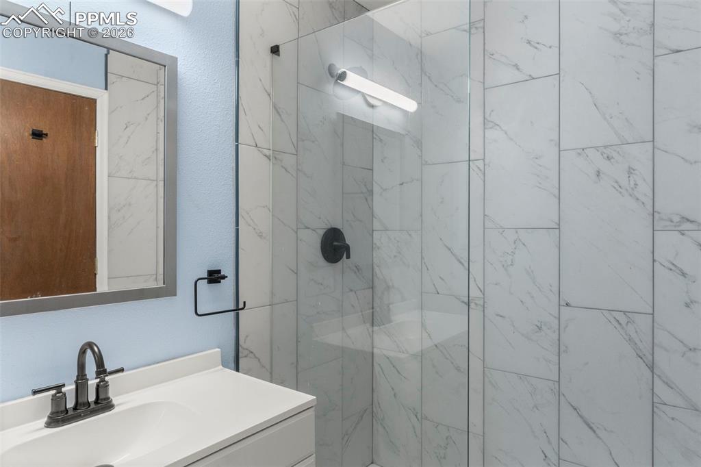 Image 45 of 50: 3/4 bathroom featuring vanity and a marble finish WALKIN shower