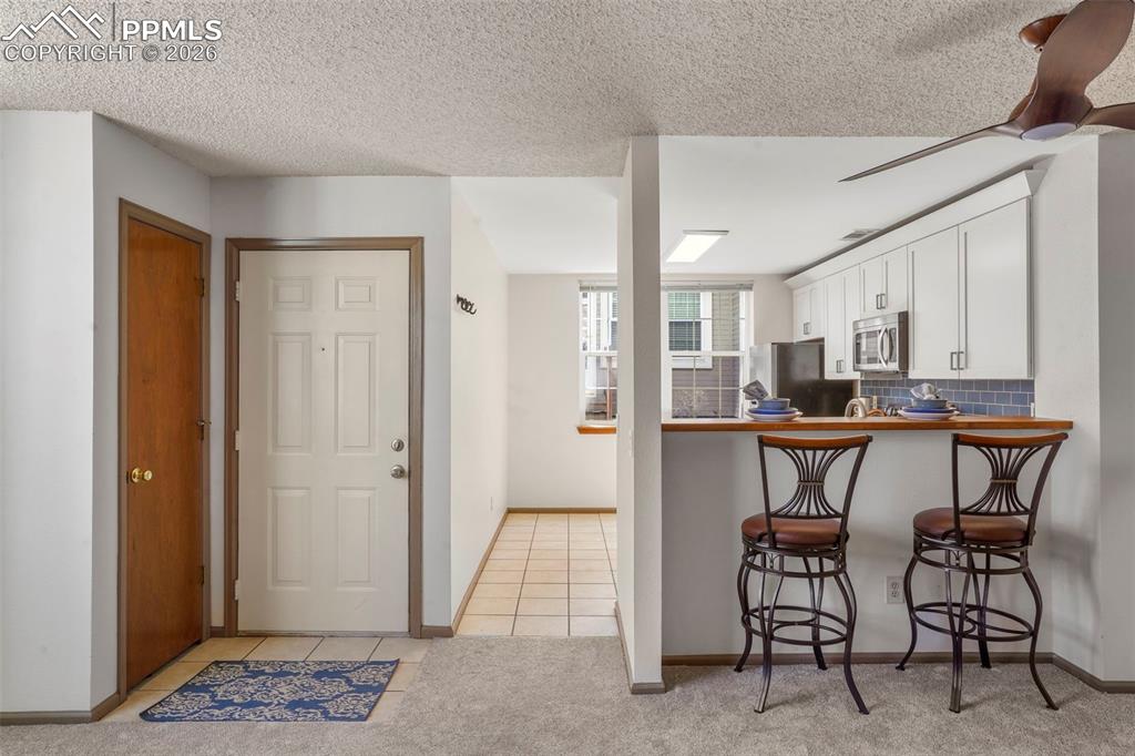 Image 6 of 50: Kitchen featuring white cabinets, light tile patterned floors, kitchen peni