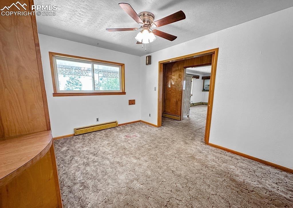 Image 10 of 19: Empty room featuring light carpet, a textured ceiling, a baseboard heating 