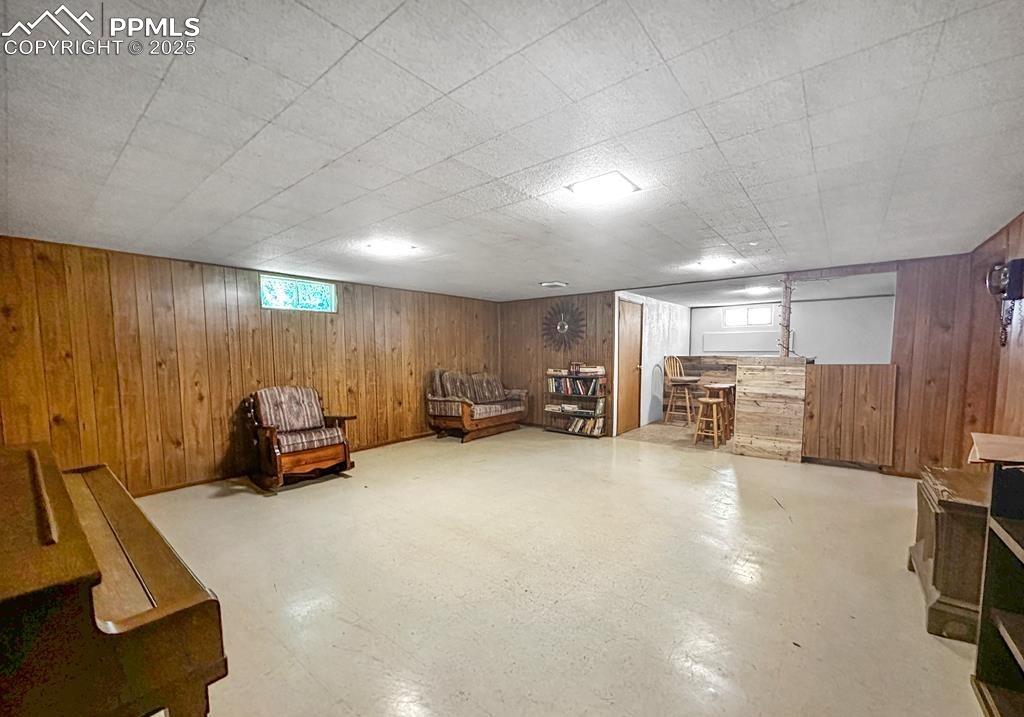 Image 13 of 19: Sitting room with wooden walls, plenty of natural light, and bar area