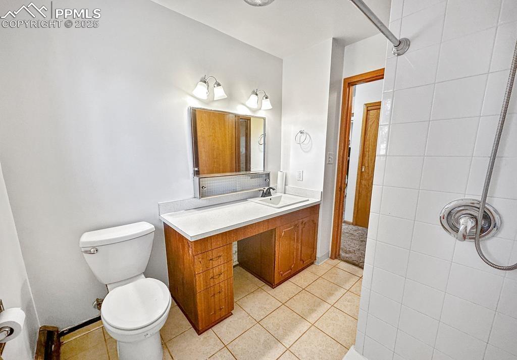 Image 4 of 19: Bathroom featuring vanity, light tile patterned floors, and tiled shower