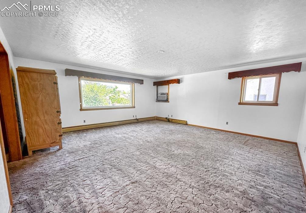 Image 6 of 19: Carpeted spare room with a textured ceiling and a baseboard radiator