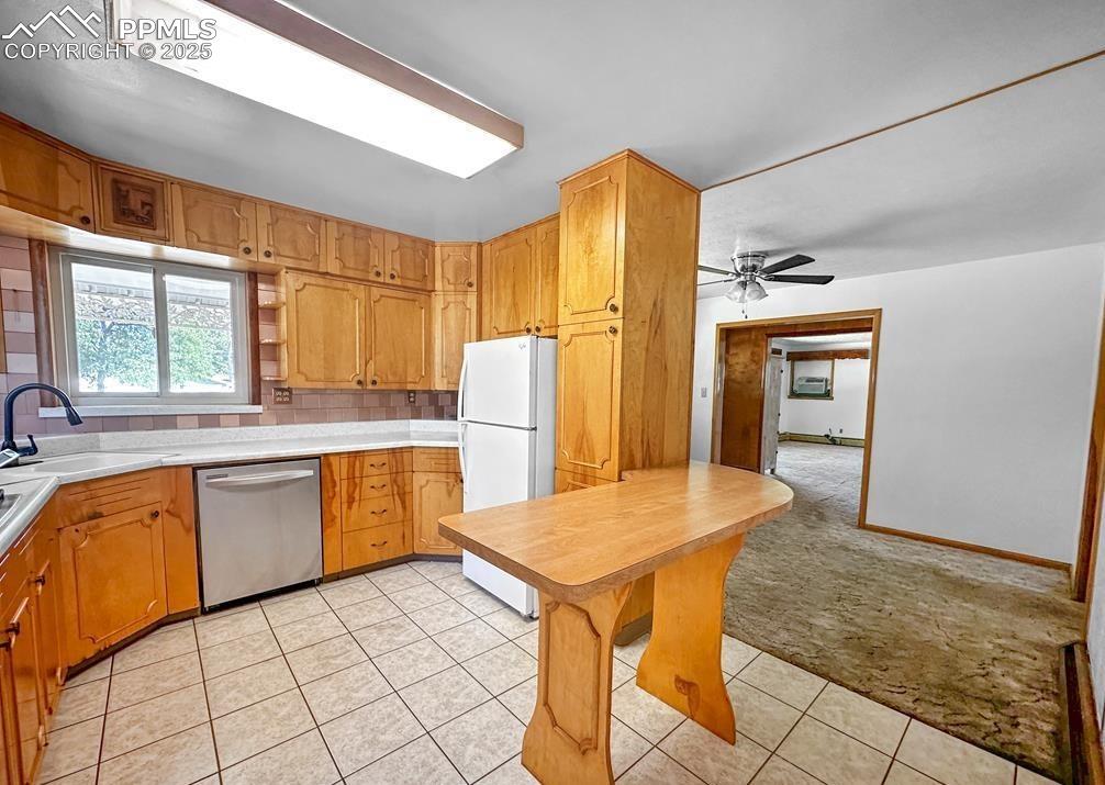 Image 7 of 19: Kitchen featuring light colored carpet, light countertops, freestanding ref