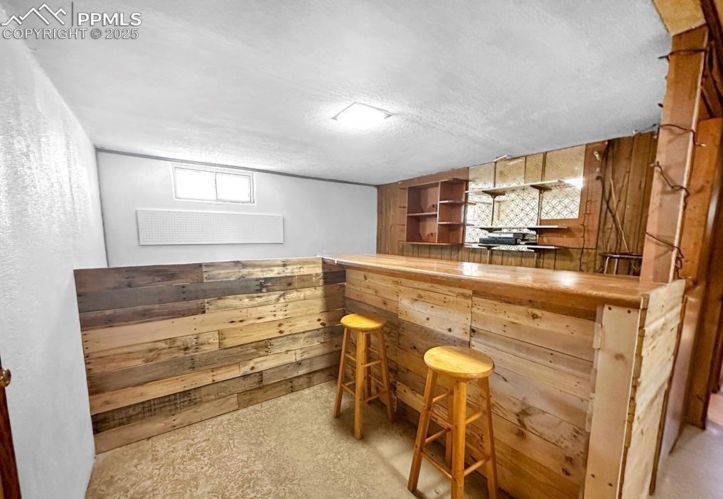 Image 8 of 19: Indoor dry bar with wooden walls, open shelves, butcher block countertops, 