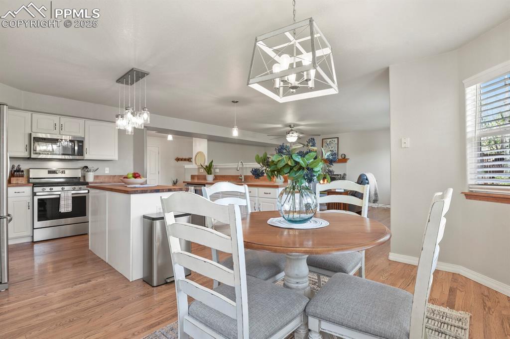 Image 10 of 50: Dining space with a chandelier, light wood-style flooring, and ceiling fan