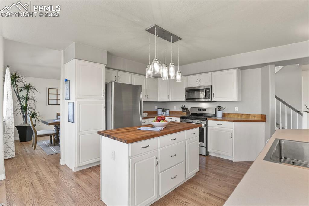 Image 12 of 50: Kitchen featuring appliances with stainless steel finishes, wooden counters