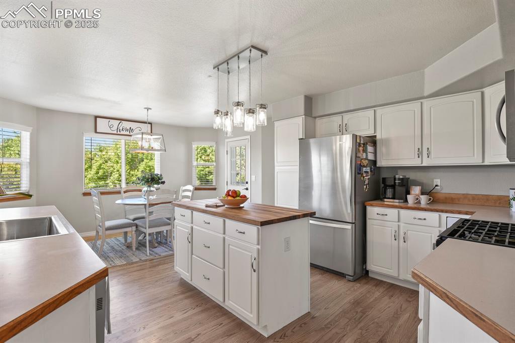 Image 13 of 50: Kitchen with freestanding refrigerator, a kitchen island, wood counters, li