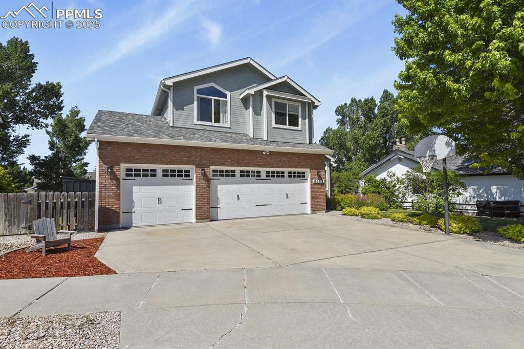 Image 2 of 50: View of front of house with brick siding, an attached garage, and driveway