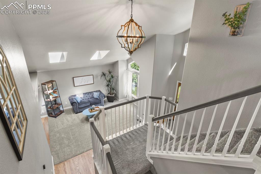 Image 20 of 50: Staircase with a skylight, a chandelier, and wood finished floors