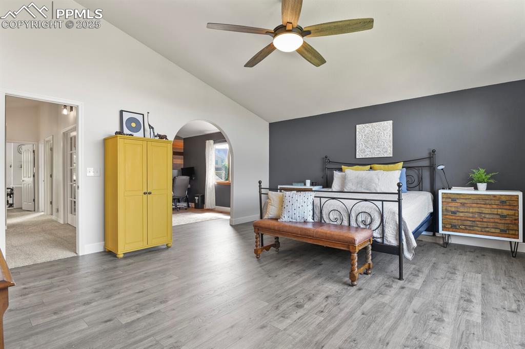 Image 21 of 50: Bedroom featuring arched walkways, light wood-type flooring, high vaulted c