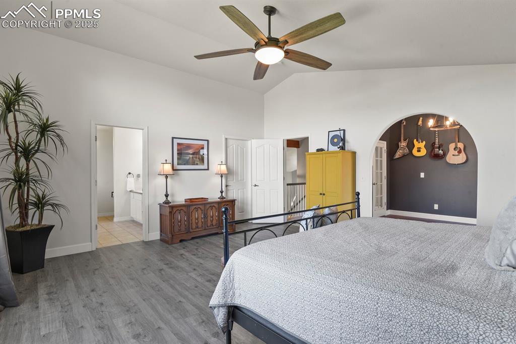 Image 22 of 50: Bedroom with high vaulted ceiling, light wood-type flooring, arched walkway