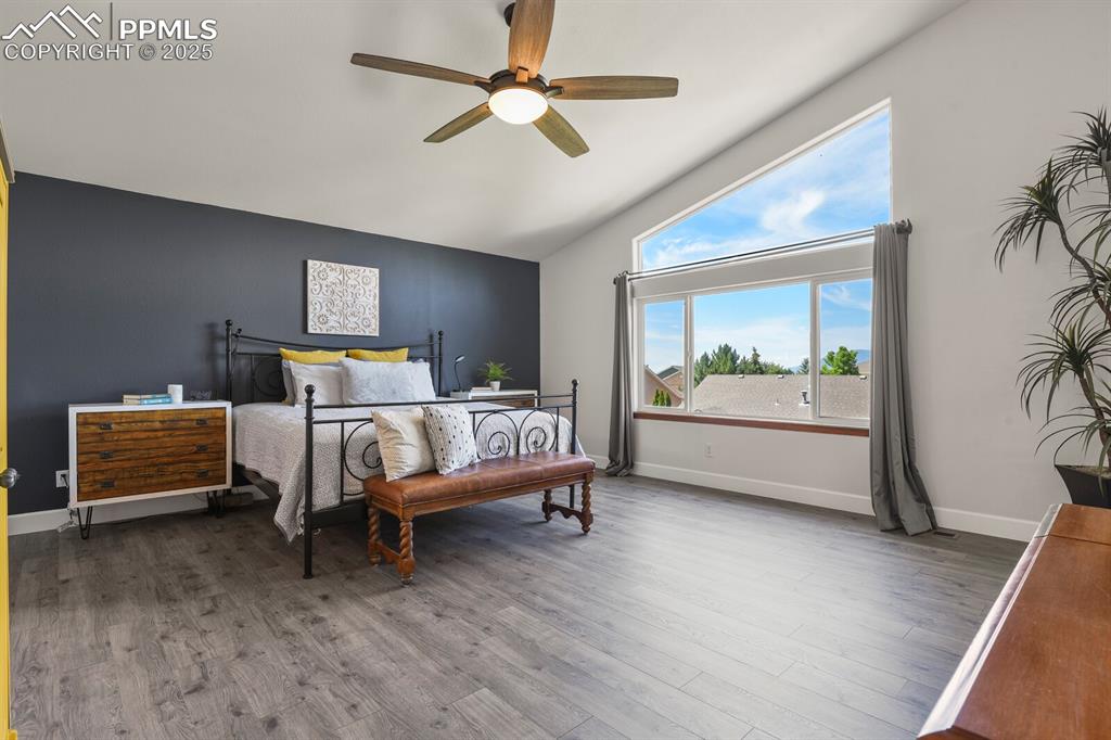 Image 23 of 50: Bedroom featuring vaulted ceiling, multiple windows, wood finished floors, 