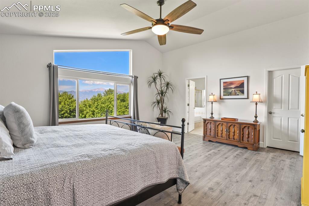 Image 24 of 50: Bedroom featuring wood finished floors, high vaulted ceiling, ceiling fan, 