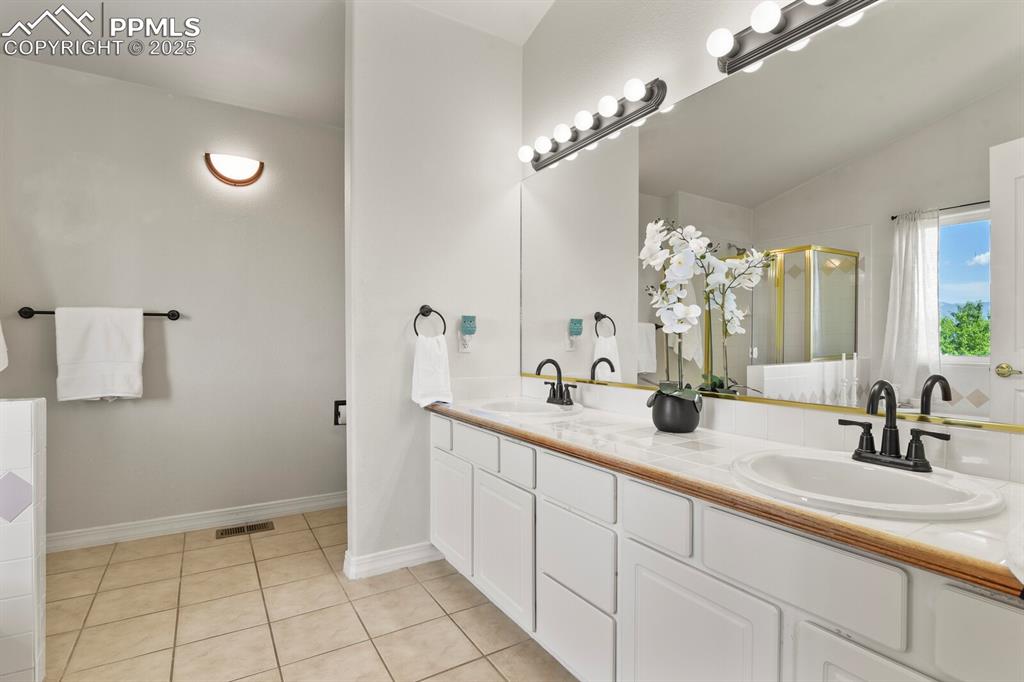 Image 26 of 50: Bathroom with double vanity, a shower stall, and tile patterned floors