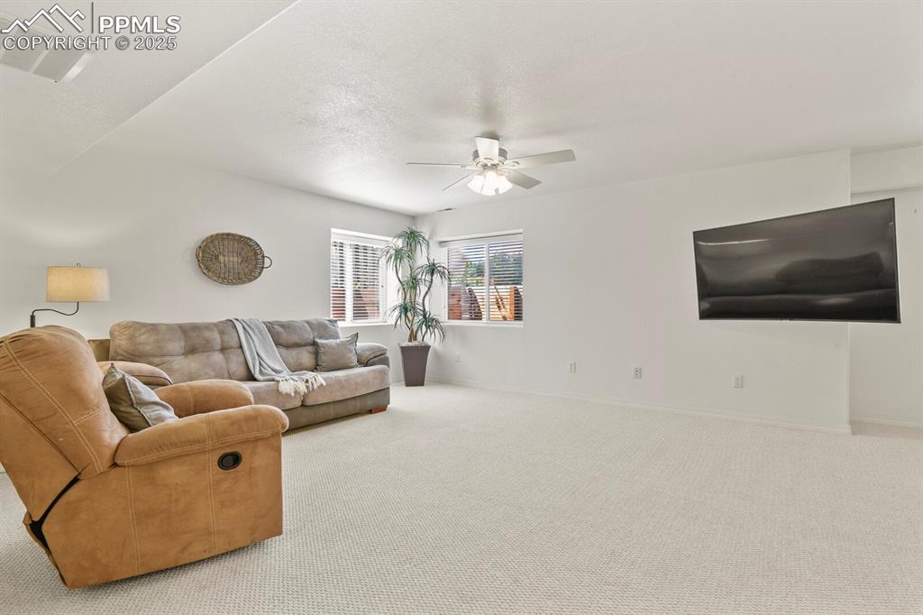 Image 34 of 50: Carpeted living area with ceiling fan and baseboards