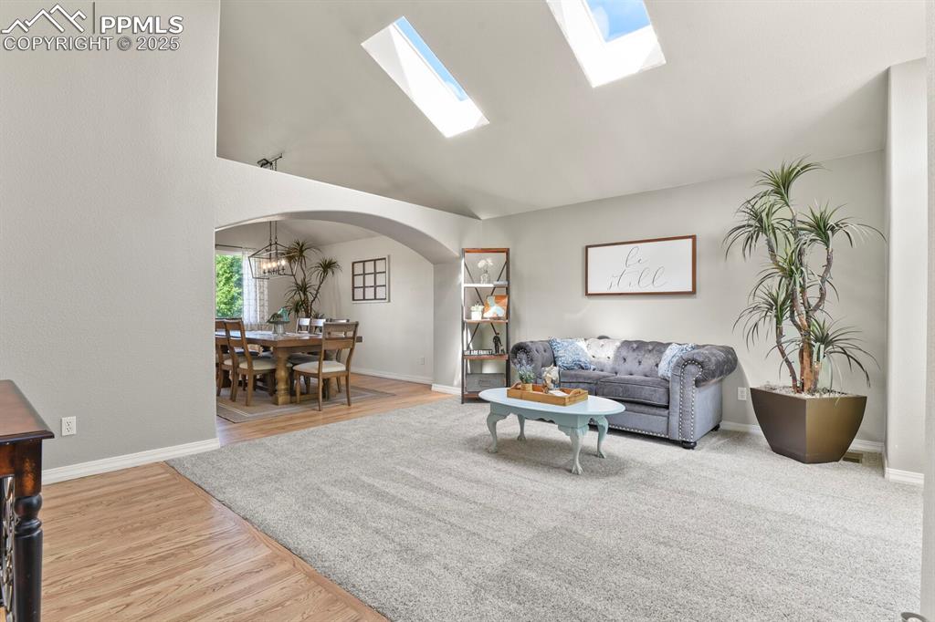 Image 6 of 50: Living area with arched walkways, wood finished floors, high vaulted ceilin