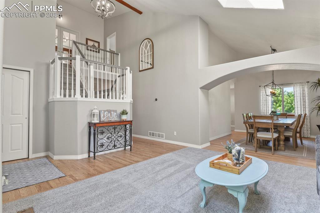 Image 8 of 50: Living room featuring arched walkways, high vaulted ceiling, wood finished 