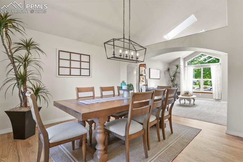 Image 9 of 50: Dining space featuring arched walkways, light wood-style floors, and vaulte