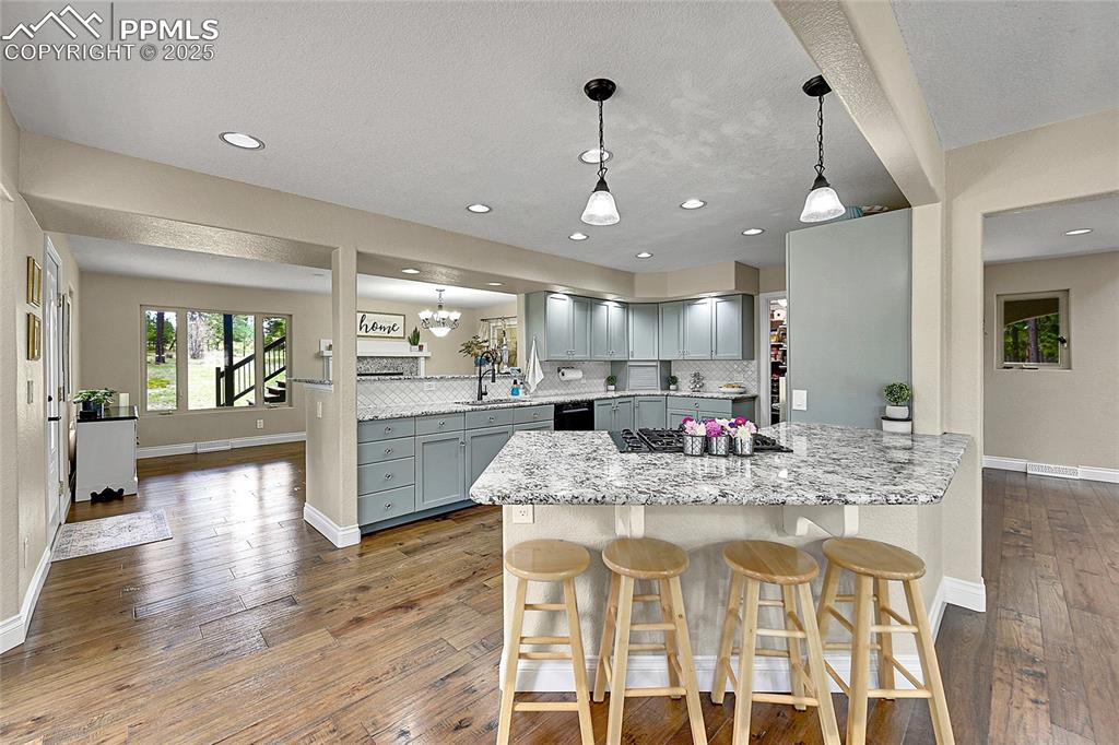 Image 12 of 50: Kitchen featuring a kitchen breakfast bar,  solid wood cabinetry, granite c