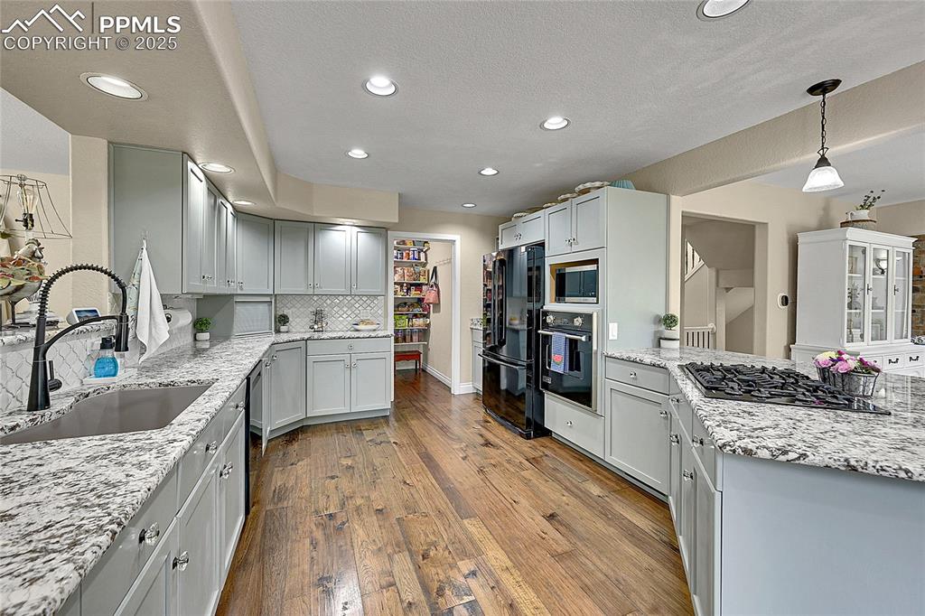 Image 13 of 50: Kitchen featuring gas range in peninsula, pendant lighting, black appliance