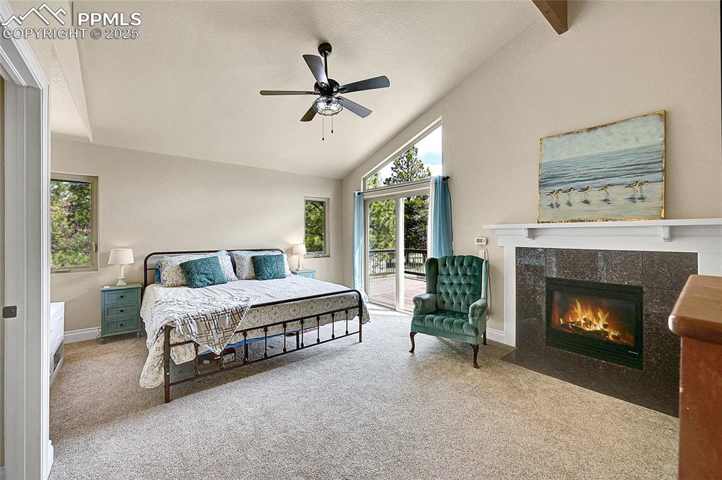 Image 16 of 50: featuring a tiled fireplace, ceiling fan, vaulted ceiling, and walk out to