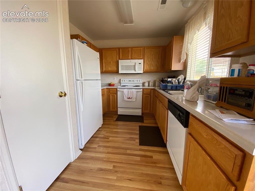 Image 2 of 9: Kitchen featuring wood-finish flooring, light wood cabinetry, white applian