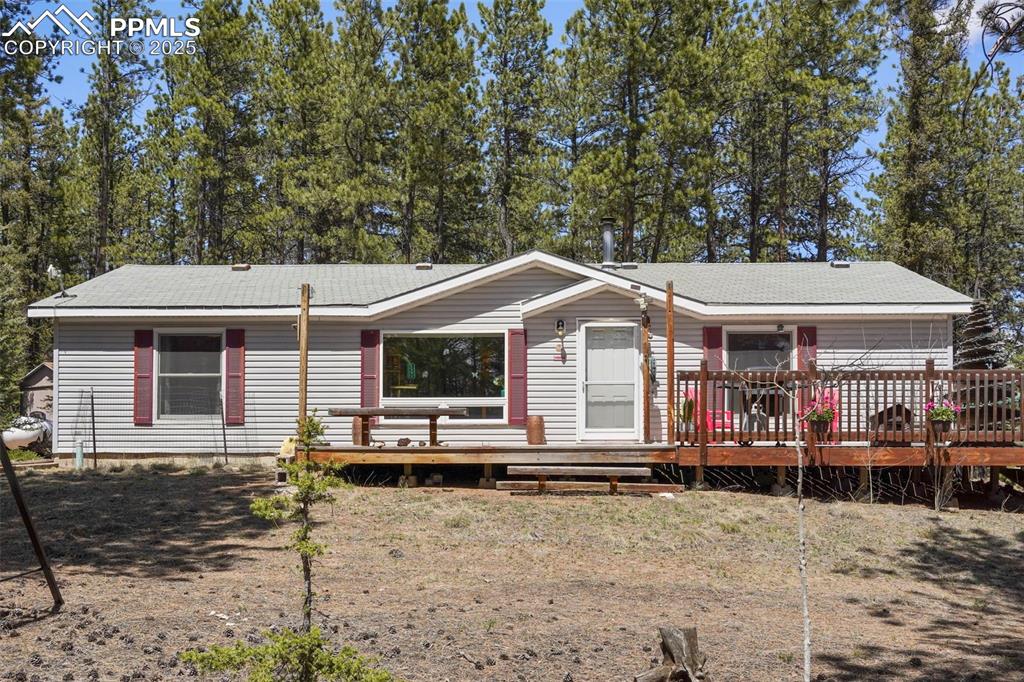Caption: View of front of home featuring a deck and roof with shingles