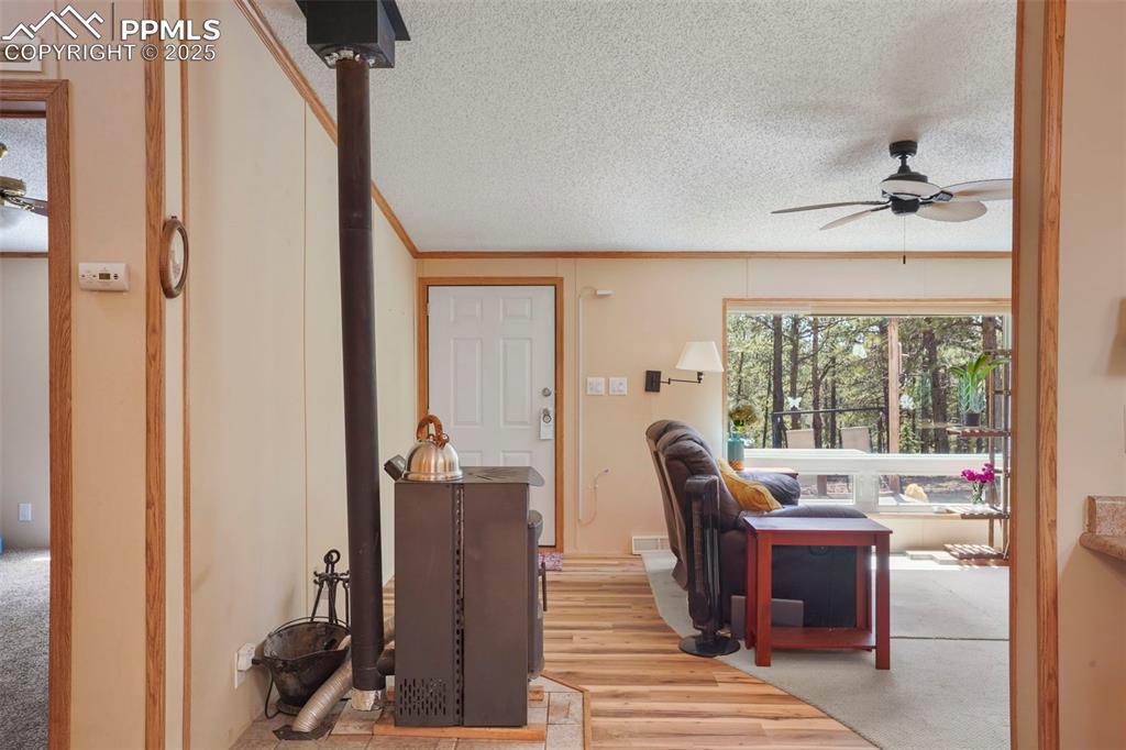 Image 5 of 29: Living room featuring a ceiling fan, a textured ceiling, ornamental molding