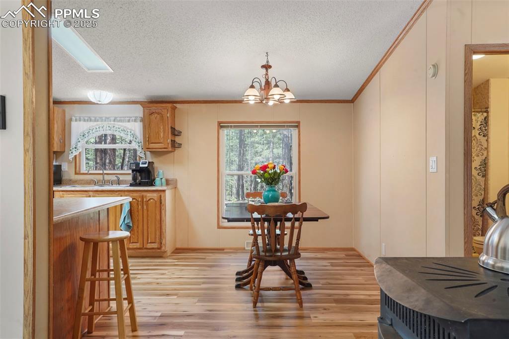 Image 7 of 29: Dining space with light wood finished floors, ornamental molding, a texture